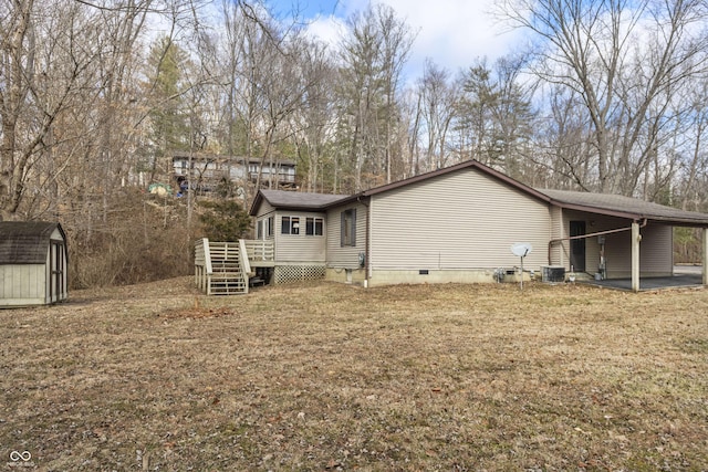 rear view of house featuring an outbuilding, a lawn, crawl space, a shed, and cooling unit