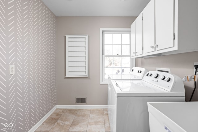 laundry area with washer and clothes dryer, visible vents, cabinet space, an accent wall, and a sink