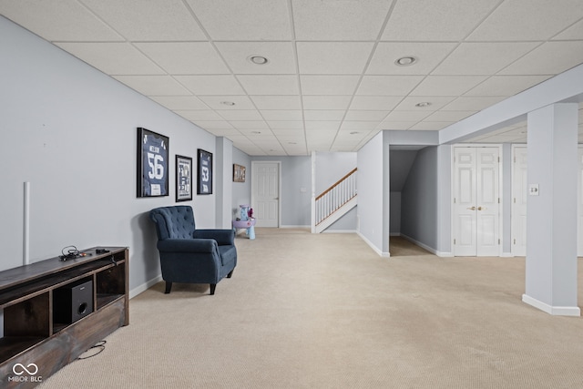 living area featuring stairway, carpet flooring, a paneled ceiling, and baseboards