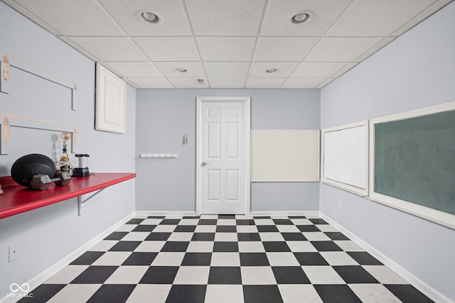 interior space with baseboards, a paneled ceiling, and tile patterned floors