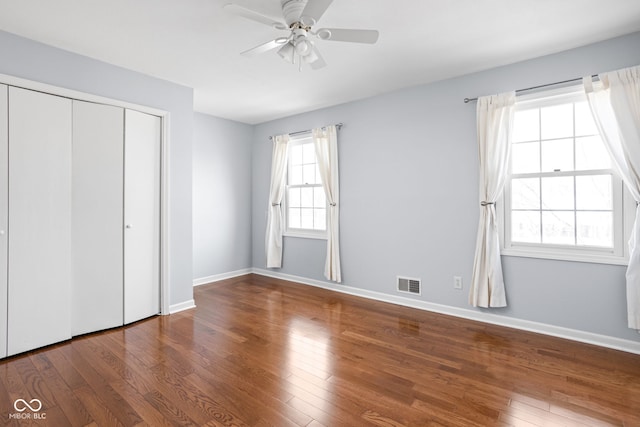 unfurnished bedroom with wood-type flooring, visible vents, and baseboards