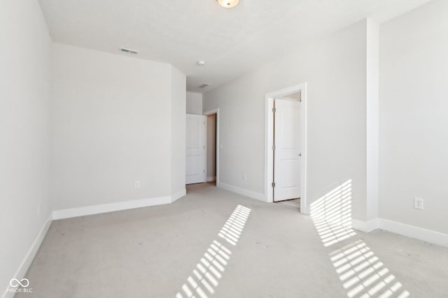 unfurnished bedroom featuring baseboards, visible vents, and light colored carpet