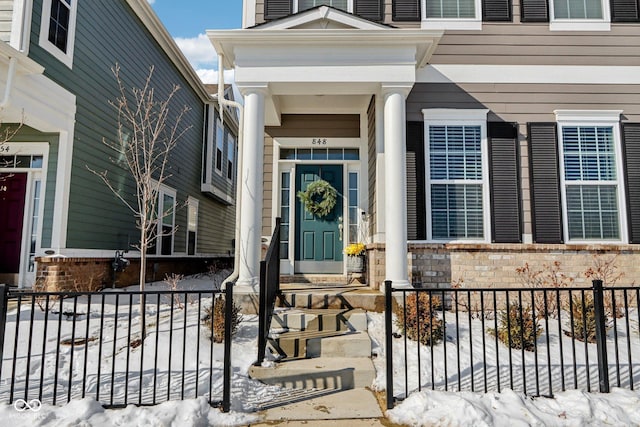 snow covered property entrance with brick siding