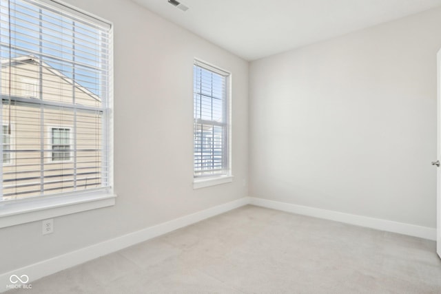 spare room featuring light carpet, visible vents, and baseboards