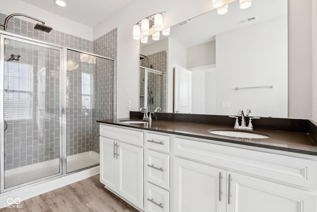 full bathroom with wood finished floors, a stall shower, a sink, and visible vents