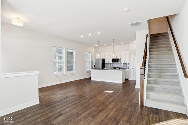 unfurnished living room with baseboards, visible vents, dark wood finished floors, stairway, and recessed lighting