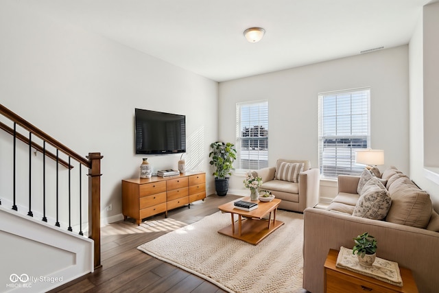 living area with stairway, wood finished floors, visible vents, and baseboards