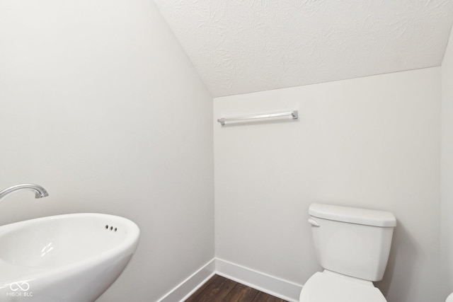 bathroom featuring baseboards, toilet, wood finished floors, a textured ceiling, and a sink