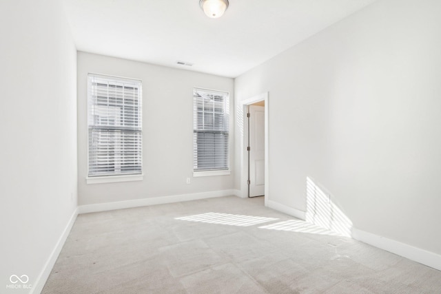 empty room with visible vents, baseboards, and light colored carpet