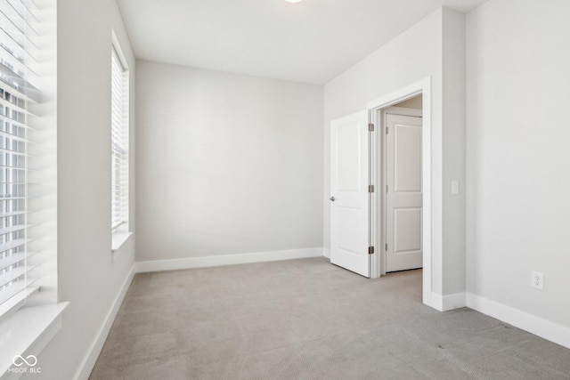 unfurnished bedroom with light carpet, multiple windows, and baseboards