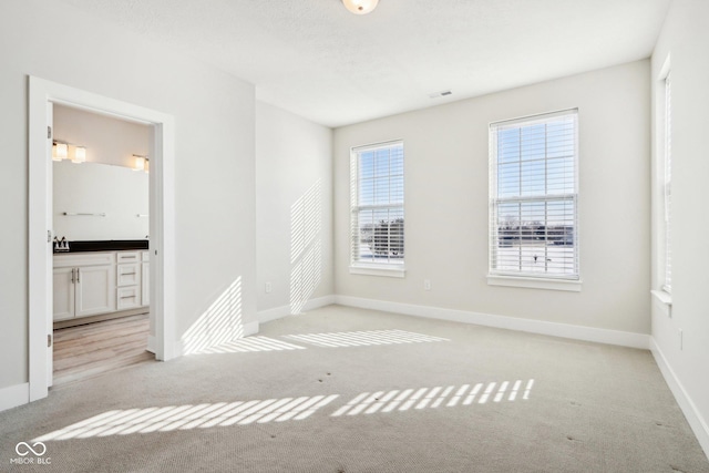 unfurnished room featuring visible vents, light carpet, and baseboards