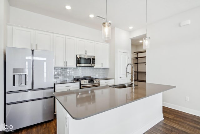 kitchen featuring stainless steel appliances, decorative light fixtures, a sink, and white cabinetry