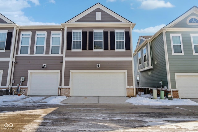 view of front of home with brick siding, an attached garage, and central AC unit