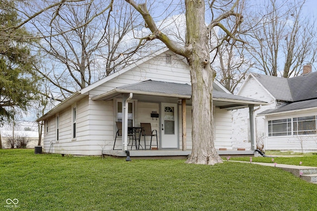 bungalow featuring covered porch, a front lawn, and central air condition unit