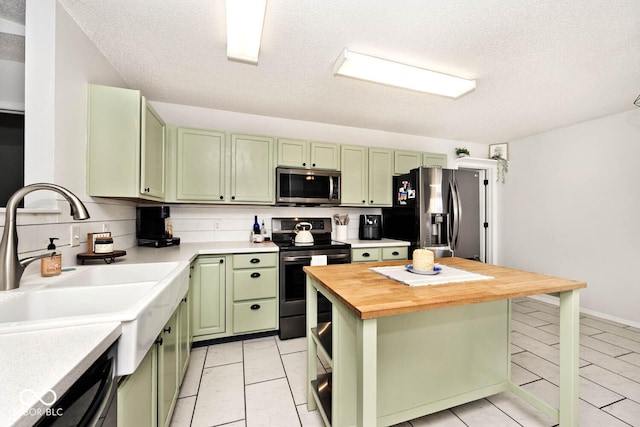 kitchen with butcher block countertops, sink, green cabinets, appliances with stainless steel finishes, and tasteful backsplash