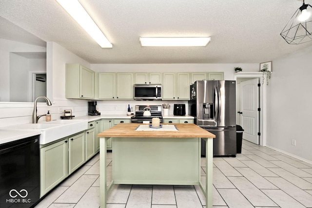 kitchen with sink, green cabinetry, wooden counters, appliances with stainless steel finishes, and backsplash