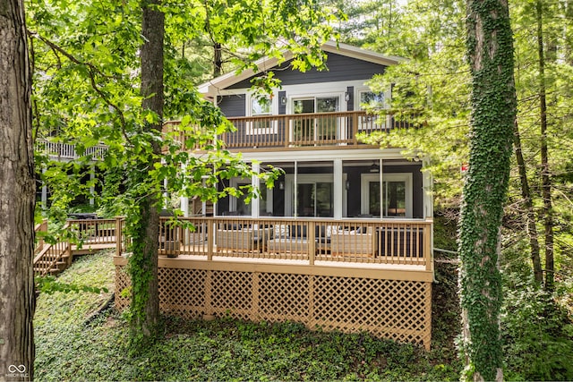 back of property with a wooden deck and a sunroom