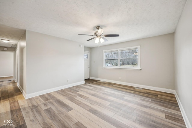 empty room featuring ceiling fan, a textured ceiling, and light hardwood / wood-style floors