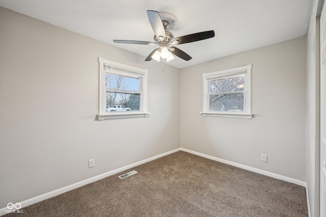 empty room with plenty of natural light, ceiling fan, and carpet