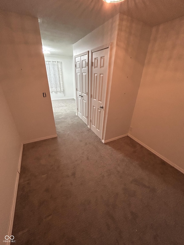 hall with dark colored carpet