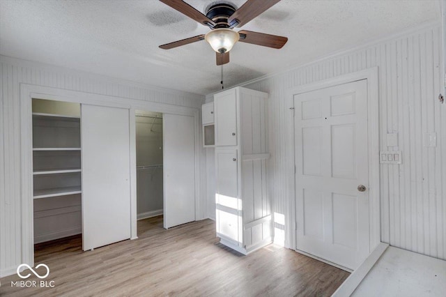 1002 Payton Ave, Indianapolis, IN 46219 - unfurnished bedroom featuring ornamental molding, two closets, a textured ceiling, and light hardwood / wood-style flooring