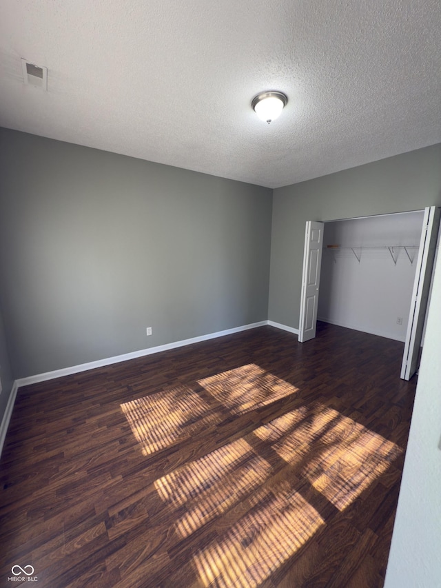 unfurnished bedroom featuring dark wood-type flooring, a closet, and a textured ceiling