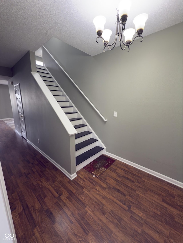 stairs featuring hardwood / wood-style flooring, a textured ceiling, and a chandelier