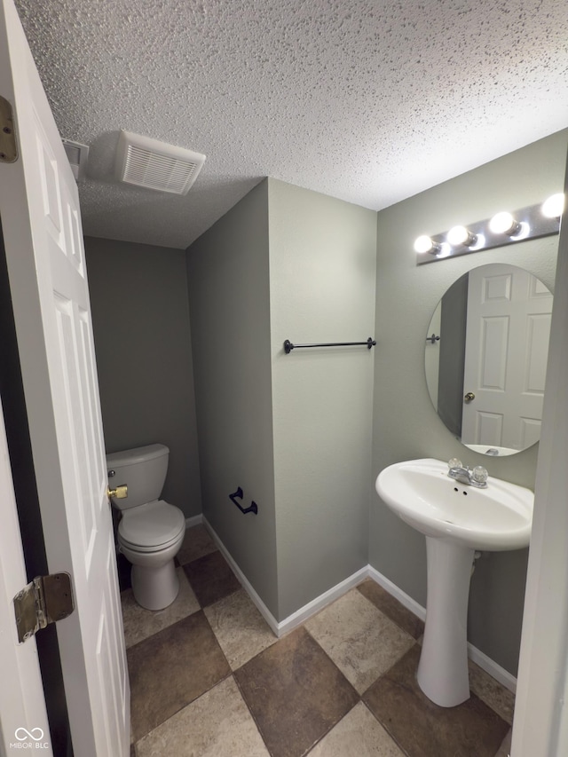 bathroom with sink, a textured ceiling, and toilet