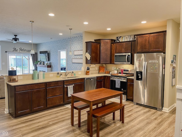 kitchen featuring sink, hanging light fixtures, stainless steel appliances, dark brown cabinetry, and light hardwood / wood-style floors