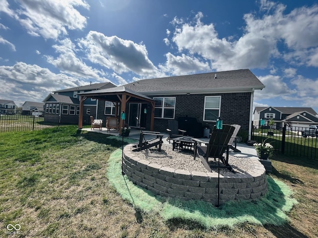 rear view of property with a fire pit, brick siding, fence, a lawn, and a patio area