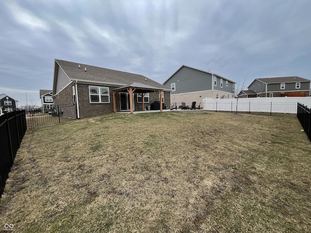 back of house featuring a lawn, a patio, a fenced backyard, a gazebo, and brick siding