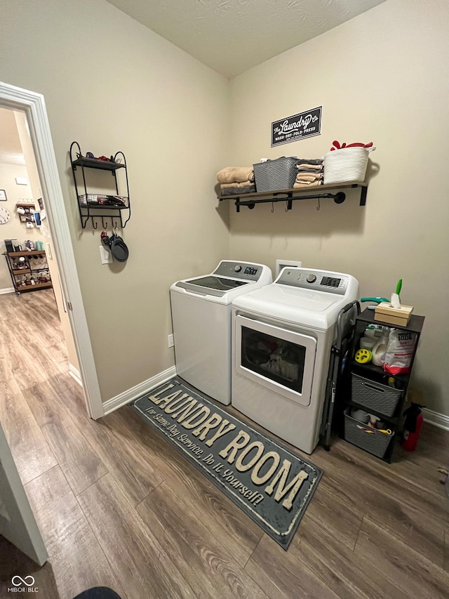 laundry area featuring wood finished floors, laundry area, baseboards, and separate washer and dryer