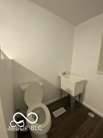 bathroom with toilet, baseboards, and wood finished floors