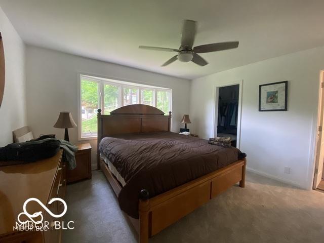 bedroom featuring light carpet, baseboards, and a ceiling fan