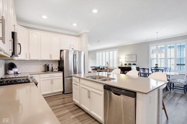 kitchen featuring sink, appliances with stainless steel finishes, a kitchen island with sink, white cabinets, and a kitchen bar