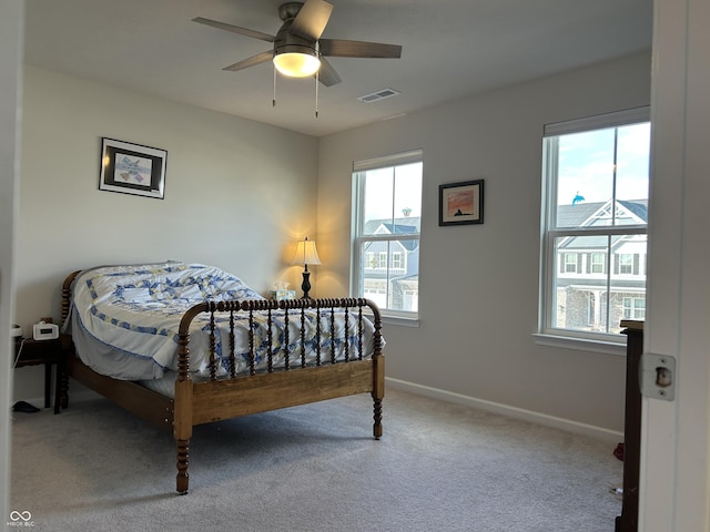 carpeted bedroom featuring multiple windows and ceiling fan