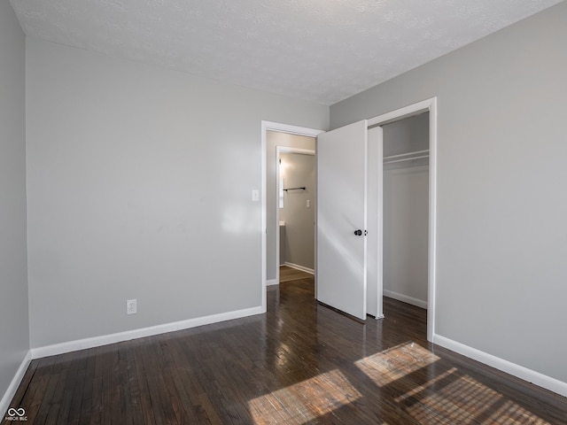 unfurnished bedroom with a closet, dark hardwood / wood-style floors, and a textured ceiling