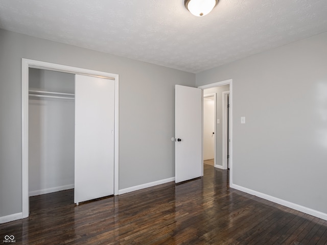 unfurnished bedroom featuring dark hardwood / wood-style flooring, a closet, and a textured ceiling