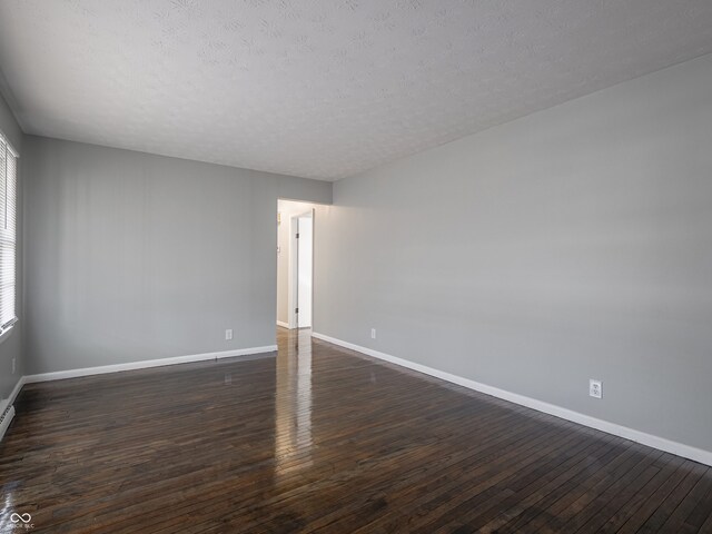 unfurnished room featuring dark wood-type flooring and a textured ceiling