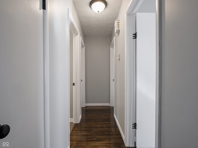 hall with dark hardwood / wood-style flooring and a textured ceiling