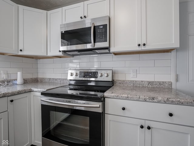 kitchen featuring white cabinetry, light stone counters, decorative backsplash, and stainless steel appliances