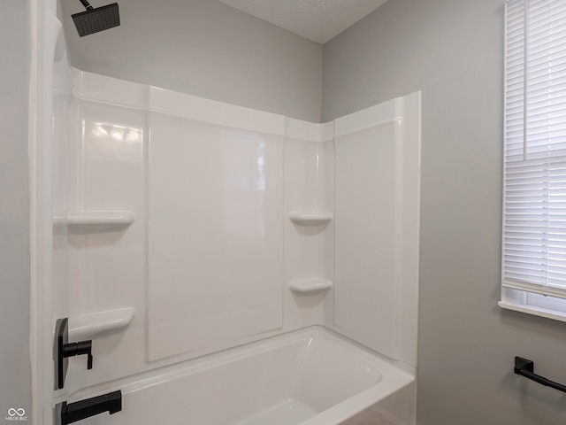 bathroom featuring bathtub / shower combination and a textured ceiling