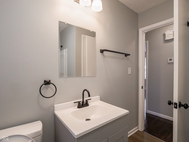 bathroom featuring vanity, wood-type flooring, and toilet