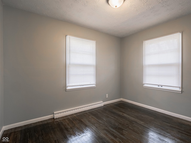 unfurnished room featuring baseboard heating, a healthy amount of sunlight, dark wood-type flooring, and a textured ceiling