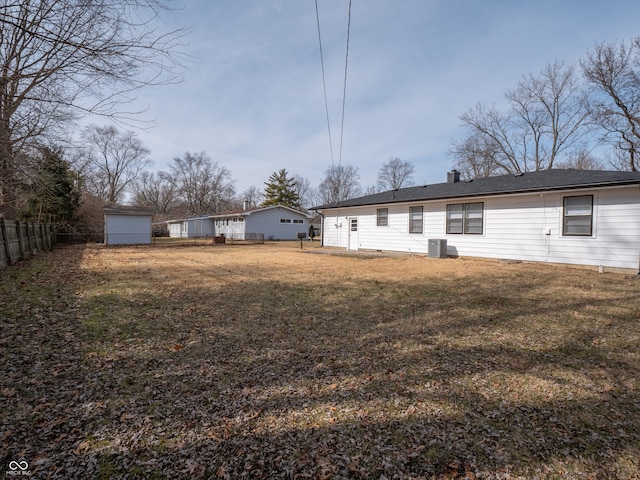 rear view of property with central AC unit and a lawn