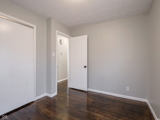 spare room featuring a textured ceiling and dark hardwood / wood-style flooring