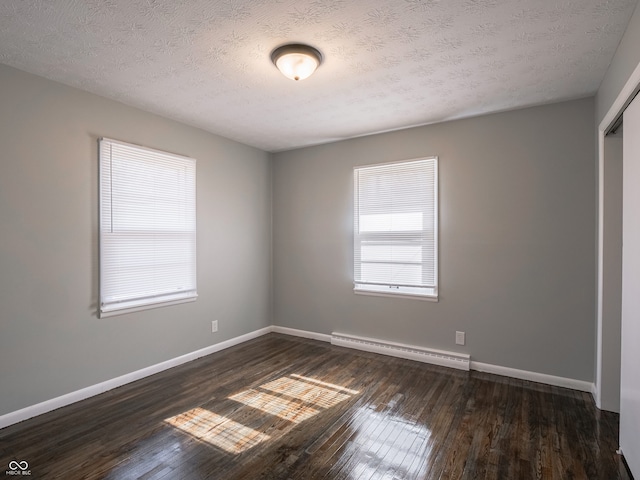 spare room with a baseboard heating unit, a textured ceiling, and dark hardwood / wood-style flooring