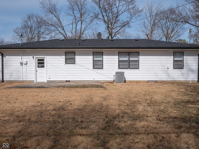 back of property with central AC and a lawn