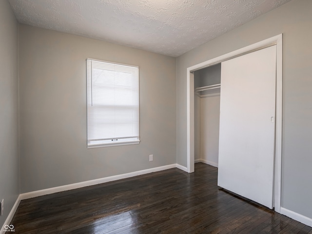 unfurnished bedroom with dark hardwood / wood-style floors, a textured ceiling, and a closet