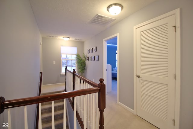 hallway featuring light carpet and a textured ceiling